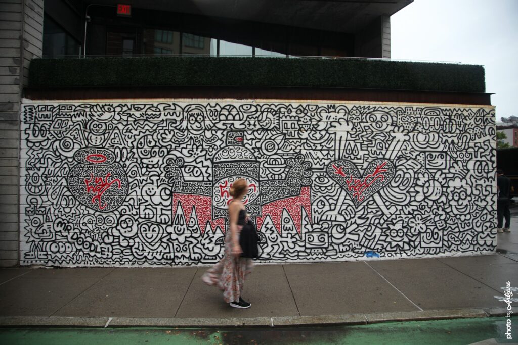 Street art de Mr Doodle montrant une grande fresque remplie de doodles noirs et de cœurs rouges sur un mur urbain à New York.