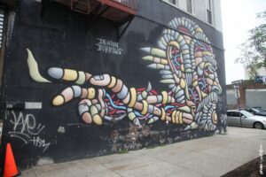 Street art de Denton Burrows montrant une grande figure colorée et symbolique peinte sur un mur à New York.
