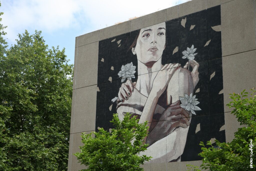 Portrait féminin en fresque murale par Tamara Alves sur un bâtiment urbain