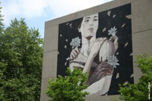 Portrait féminin en fresque murale par Tamara Alves sur un bâtiment urbain