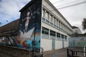 Street art de Marika montrant un enfant naviguant sur un bateau en papier peint sur un mur à Boulogne-sur-Mer.