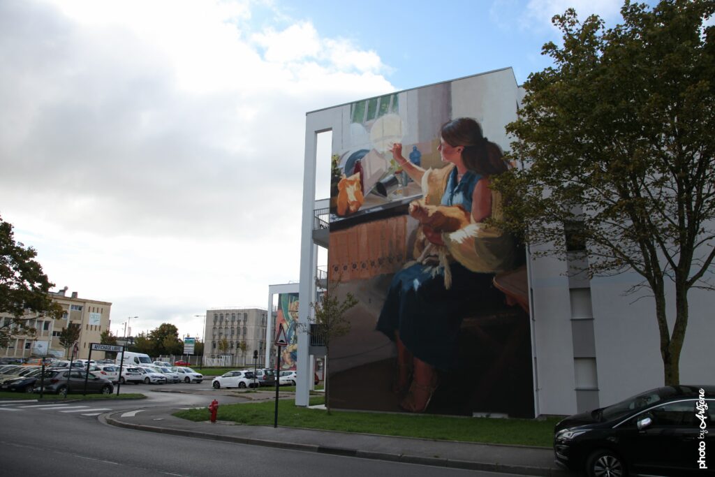 Street art réaliste de Megan Oldhue sur façade d’immeuble à Boulogne-sur-Mer représentant une femme dans une cuisine.