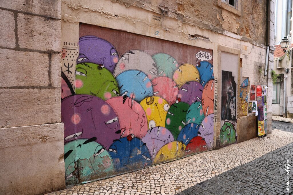Street art de Utopia montrant plusieurs personnages colorés peints sur une porte murale à Lisbonne.