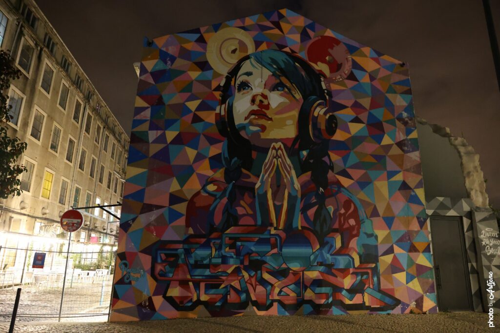Street art de Pariz One montrant un grand portrait féminin avec casque audio sur une façade à Lisbonne.