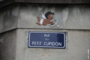 Œuvre street art MifaMosa Cupidon en mosaïque pixel art sur mur urbain