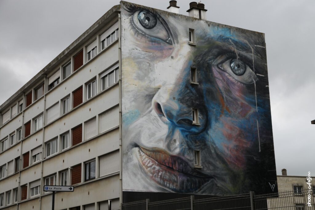 Fresque street art David Walker montrant un grand portrait coloré sur un immeuble urbain.