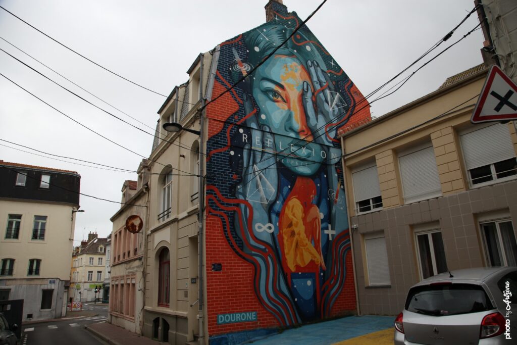 Fresque murale colorée de Dourone représentant un portrait féminin en street art