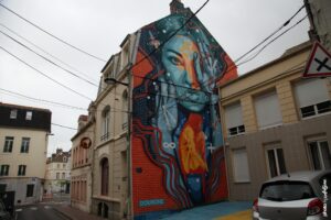 Fresque murale colorée de Dourone représentant un portrait féminin en street art