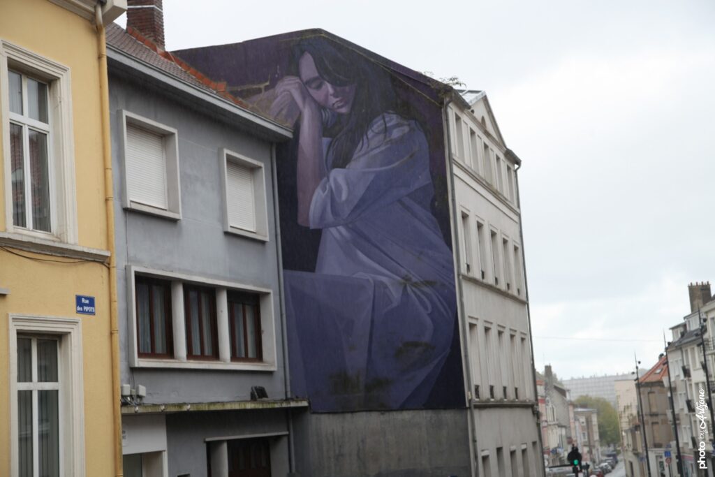 Fresque murale hyperréaliste de Lonac montrant une femme assise en tonalités violettes sur un bâtiment