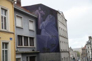 Fresque murale hyperréaliste de Lonac montrant une femme assise en tonalités violettes sur un bâtiment