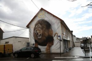 Fresque street art Scaf Oner montrant un lion hyperréaliste rugissant sur pignon