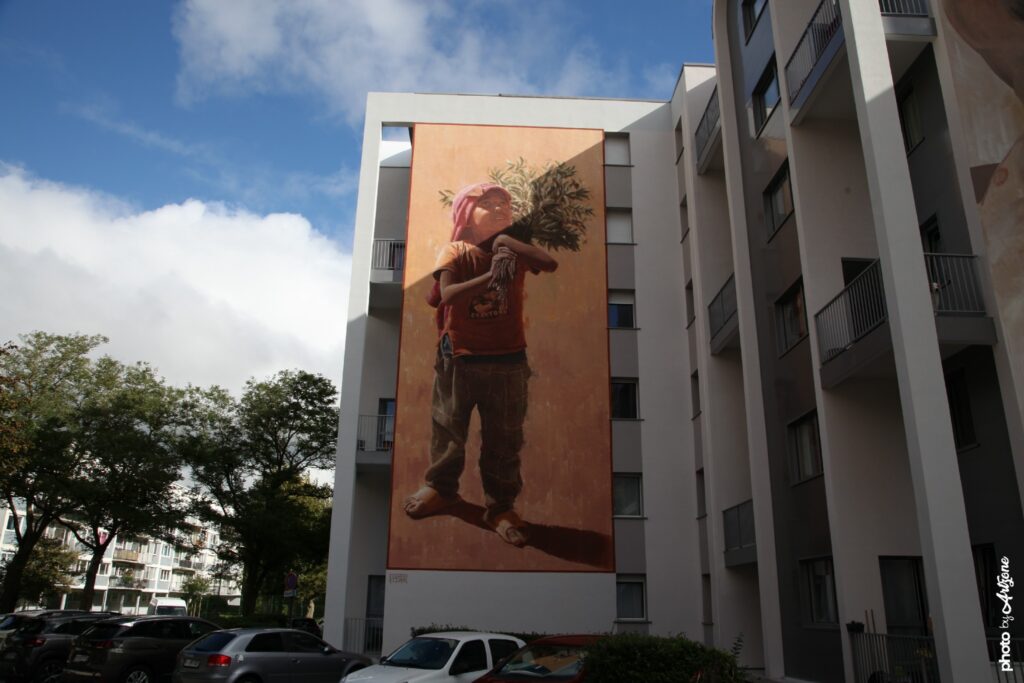 Street art monumental d’Edoardo Ettore à Boulogne-sur-Mer représentant un enfant tenant un arbre sur son épaule.