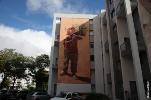 Street art monumental d’Edoardo Ettore à Boulogne-sur-Mer représentant un enfant tenant un arbre sur son épaule.