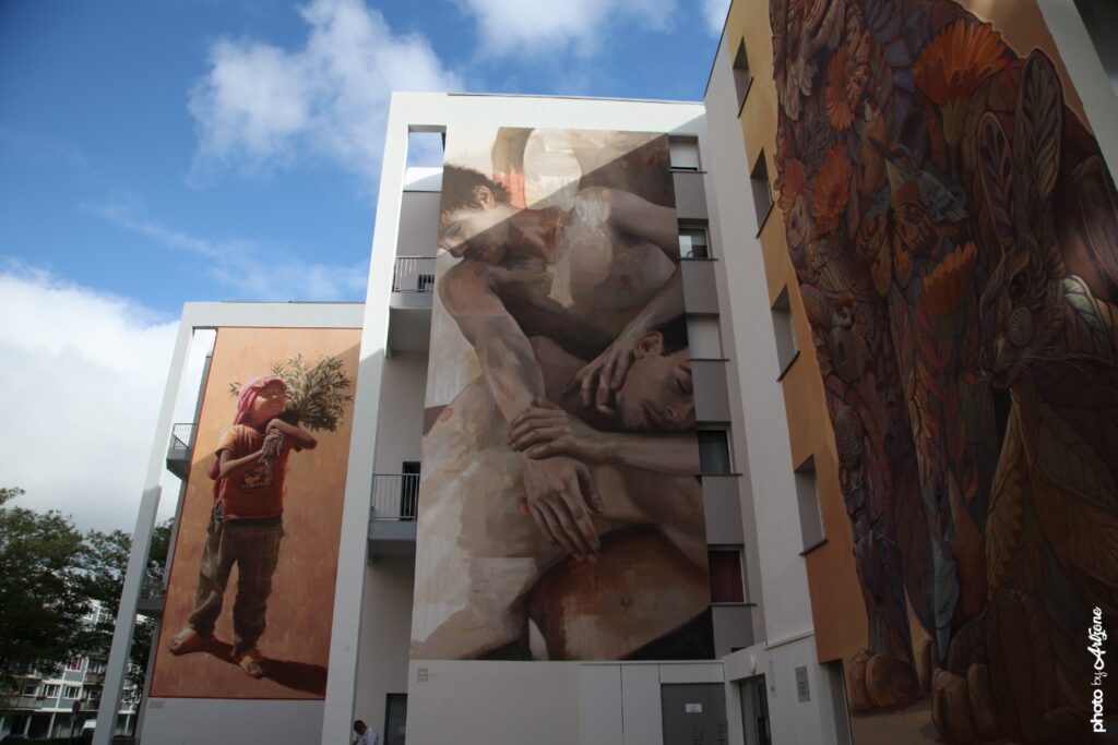 Street art de Guido Palmadessa à Boulogne-sur-Mer représentant deux figures masculines enlacées en style réaliste contemporain.