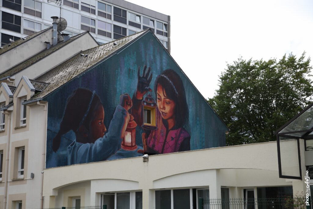 Street art d’Alaniz représentant deux enfants tenant une lanterne dans une fresque murale réaliste.